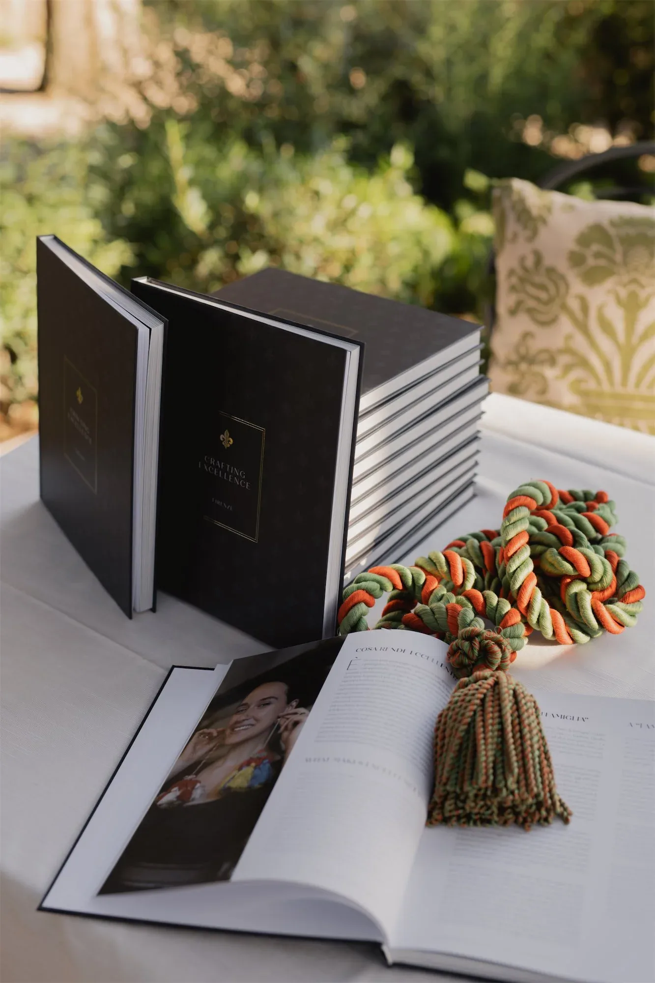 Copie del libro impilate e una aperta su un tavolo con una nappa intrecciata verde e arancio: fotografia dell'evento di presentazione
