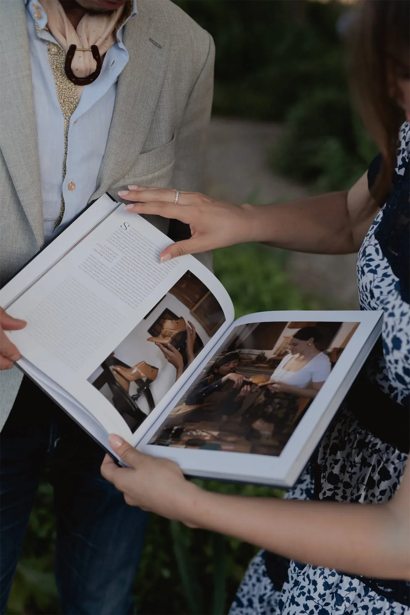 Il libro aperto fra le mani di due ospiti, con le foto delle botteghe sulle pagine: fotografia dell'evento di presentazione del libro