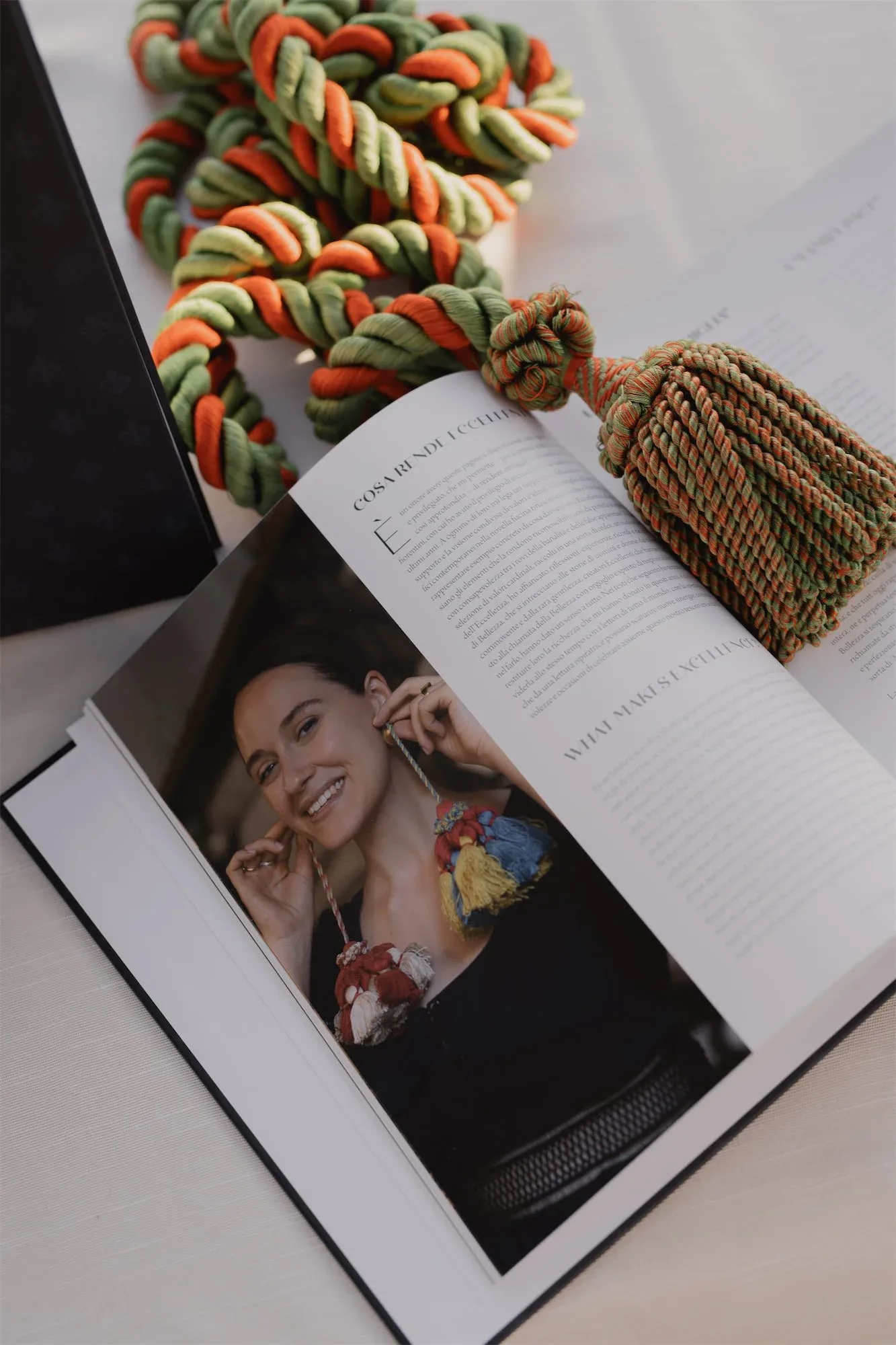 Libro aperto su un ritratto a tutta pagina con una nappa intrecciata appoggiata sopra: dettaglio dell'impaginato fotografato all'evento