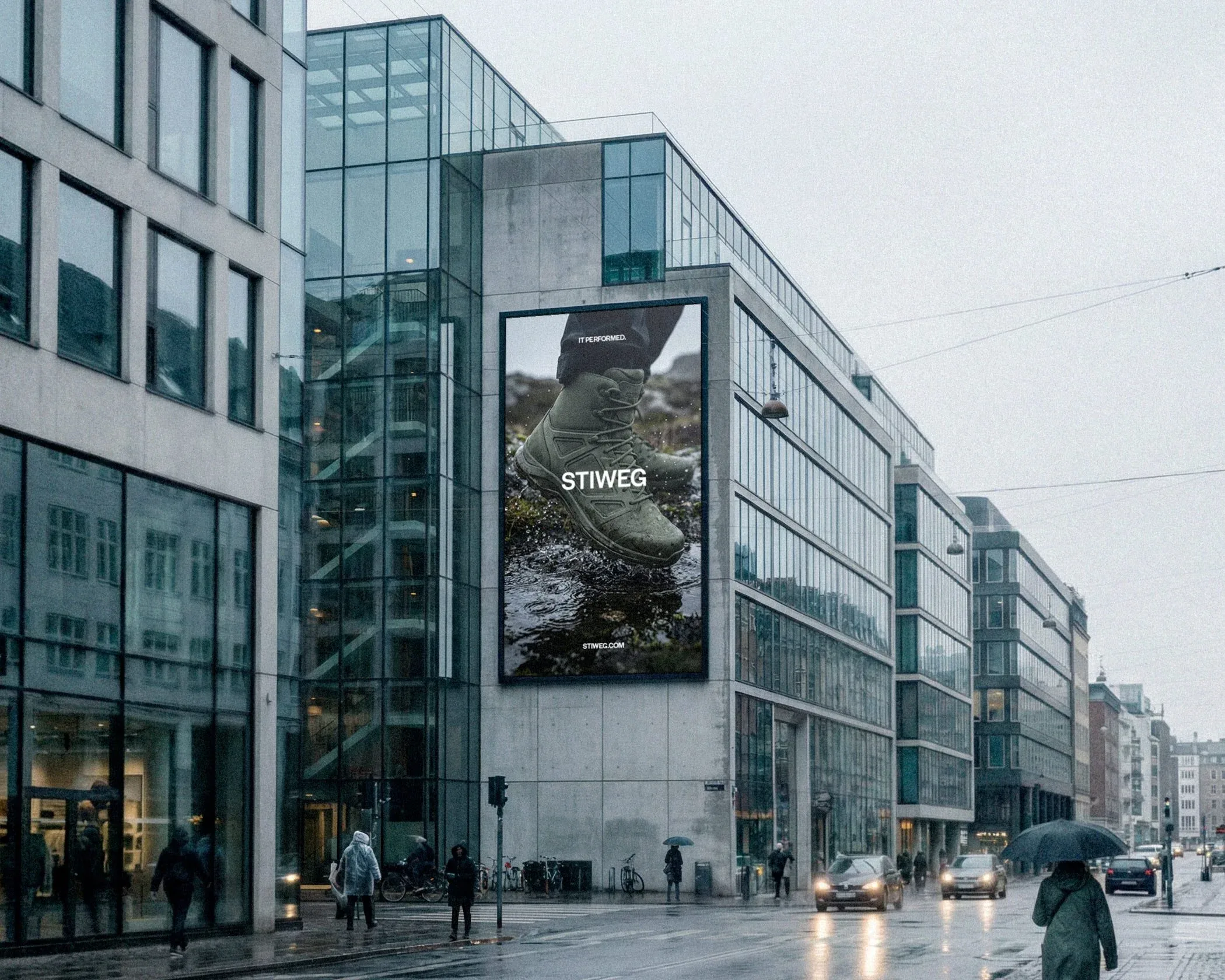 Billboard della campagna IT PERFORMED. con la scarpa TR01 nel fango su un palazzo vetrato, in una strada sotto la pioggia: mockup affissione