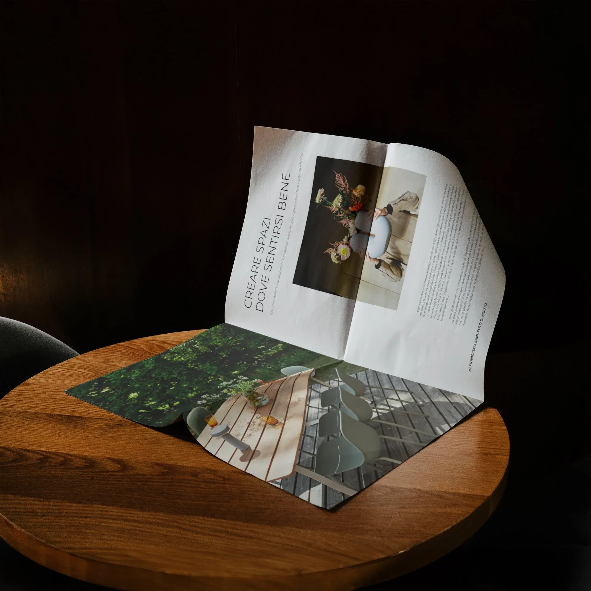 T Magazine aperto sull'articolo Creare spazi dove sentirsi bene, appoggiato su un tavolino tondo in legno in penombra: design editoriale